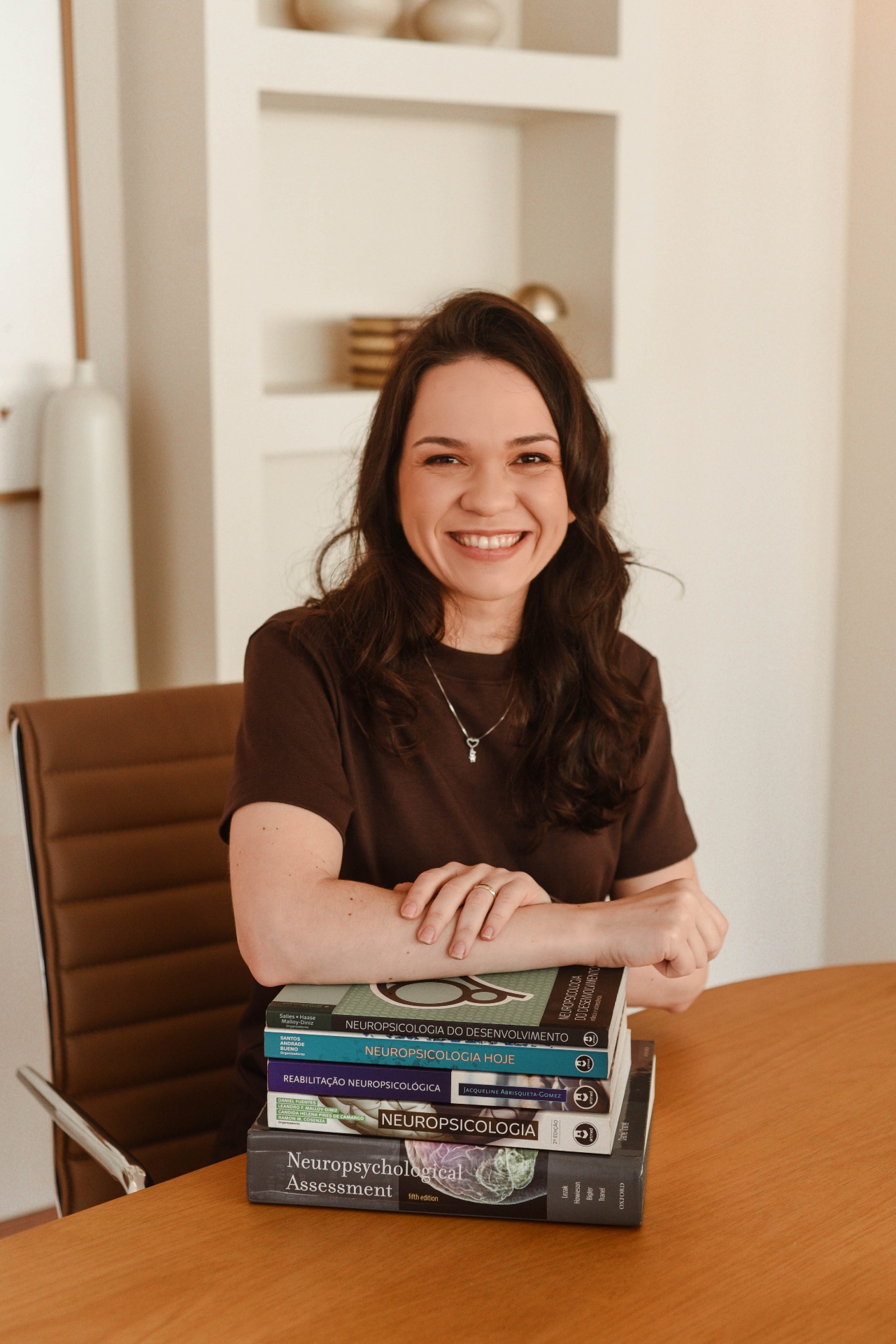 Larissa Eleutério, neuropsicóloga, em seu consultório com livros de Neuropsicologia